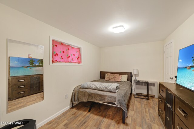 bedroom featuring radiator heating unit and light wood-type flooring