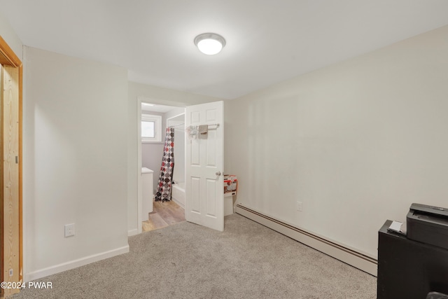 unfurnished bedroom featuring baseboard heating and light carpet