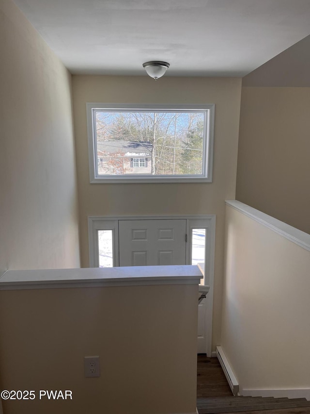 corridor featuring a baseboard heating unit, baseboards, and dark wood-style floors