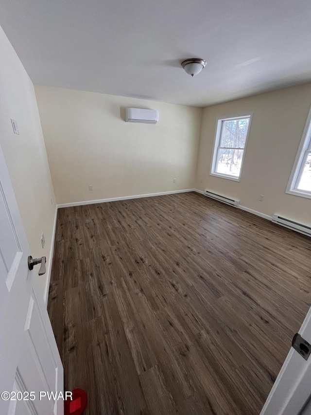 spare room featuring baseboards, a baseboard heating unit, dark wood-style flooring, and a wall mounted AC