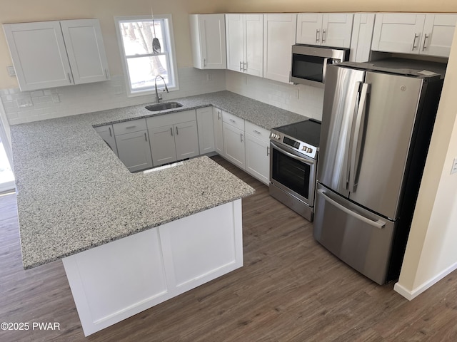 kitchen featuring stainless steel appliances, white cabinets, a sink, and wood finished floors