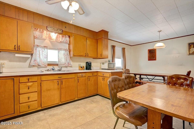 kitchen with pendant lighting, sink, ornamental molding, and ceiling fan