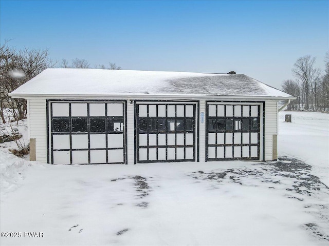 snow covered garage featuring a garage