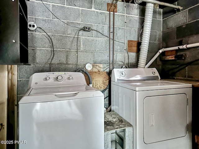 laundry room with concrete block wall, laundry area, and washing machine and dryer