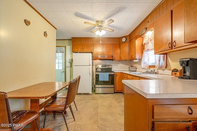 kitchen with stainless steel electric stove, sink, white fridge, ceiling fan, and crown molding