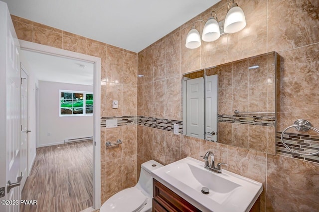 bathroom featuring a baseboard heating unit, backsplash, toilet, vanity, and tile walls