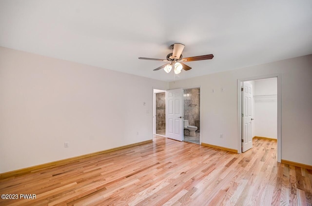 unfurnished bedroom with a walk in closet, ceiling fan, connected bathroom, light hardwood / wood-style floors, and a closet