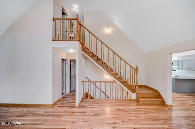 staircase featuring wood-type flooring and high vaulted ceiling