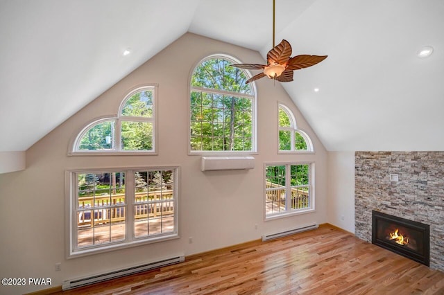 unfurnished living room featuring a stone fireplace, light hardwood / wood-style floors, a wall mounted air conditioner, and a baseboard heating unit