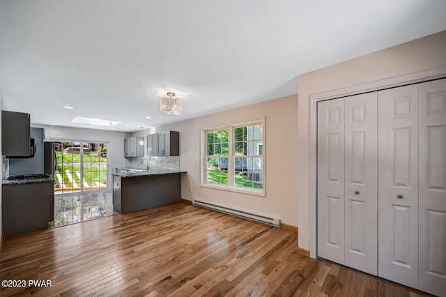 1202 Wallenpaupack Dr, Lake Ariel, PA 18436 - kitchen featuring a baseboard heating unit, wood finished floors, a skylight, dark stone counters, and a peninsula