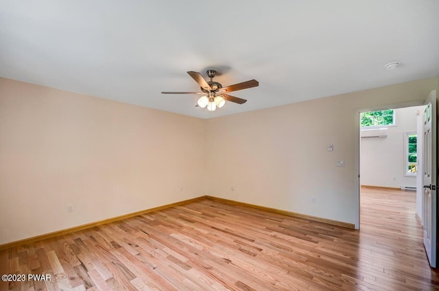 spare room featuring light hardwood / wood-style floors, a baseboard radiator, ceiling fan, and a wall unit AC