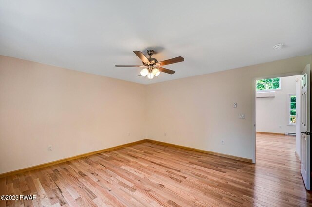 1202 Wallenpaupack Dr, Lake Ariel, PA 18436 - empty room with an AC wall unit, light wood-type flooring, a ceiling fan, baseboards, and a baseboard radiator