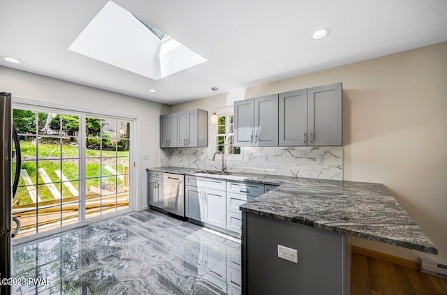 kitchen with a skylight, sink, backsplash, kitchen peninsula, and appliances with stainless steel finishes