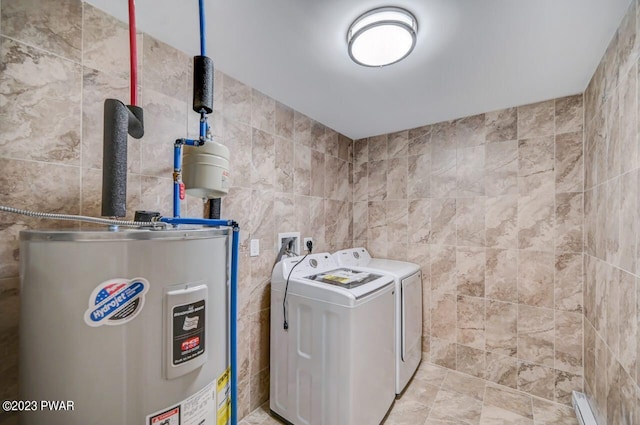 washroom featuring electric water heater, washer and clothes dryer, and tile walls