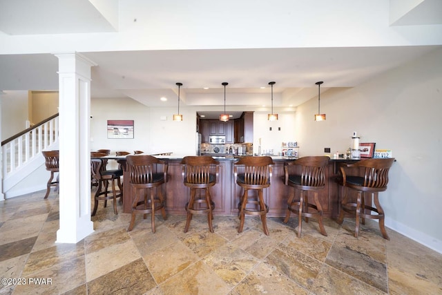 bar featuring decorative columns, dark brown cabinets, and decorative light fixtures