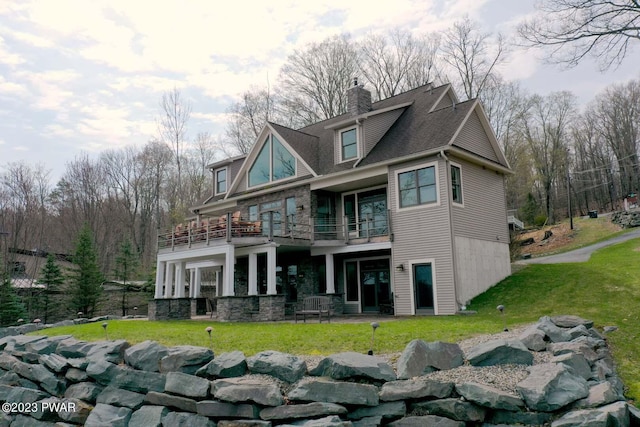 rear view of property featuring a balcony and a lawn