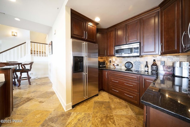 kitchen with dark brown cabinetry, backsplash, appliances with stainless steel finishes, and dark stone counters