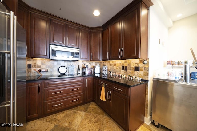 kitchen featuring tasteful backsplash, dark stone countertops, and appliances with stainless steel finishes