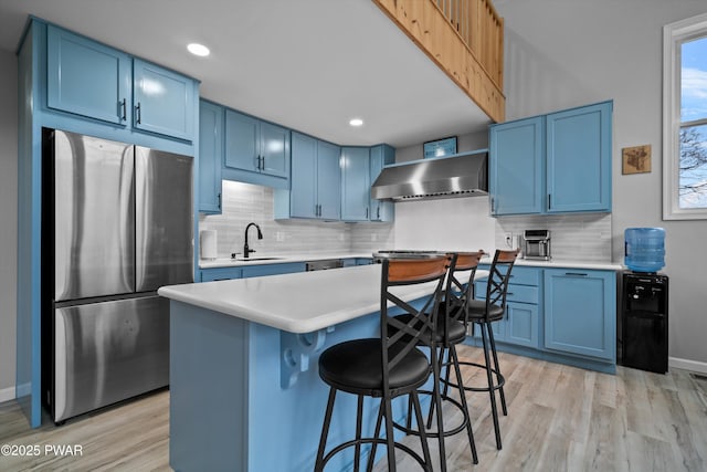 111 Riverbend Ln, Beach Lake, PA 18405 - kitchen with a sink, wall chimney range hood, freestanding refrigerator, light wood-style flooring, and blue cabinetry