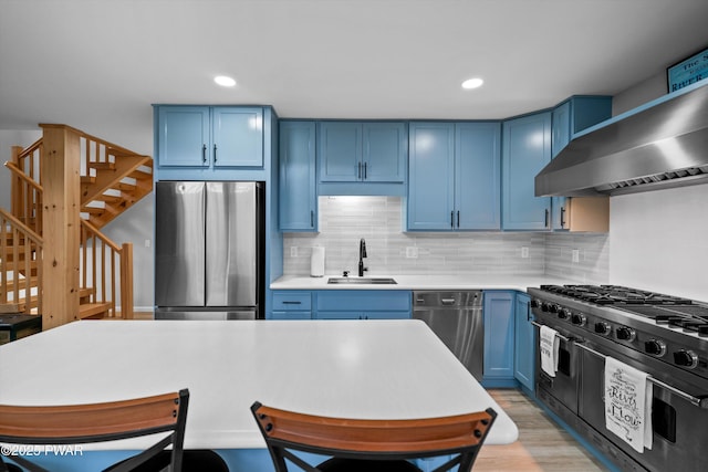 111 Riverbend Ln, Beach Lake, PA 18405 - kitchen with blue cabinets, a sink, appliances with stainless steel finishes, and wall chimney exhaust hood