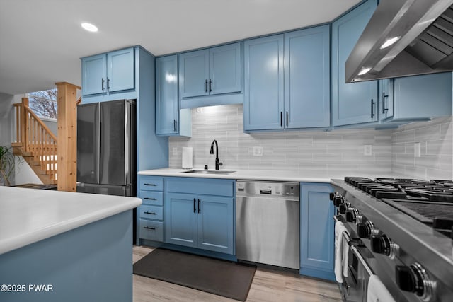 111 Riverbend Ln, Beach Lake, PA 18405 - kitchen featuring wall chimney range hood, a sink, blue cabinets, and appliances with stainless steel finishes