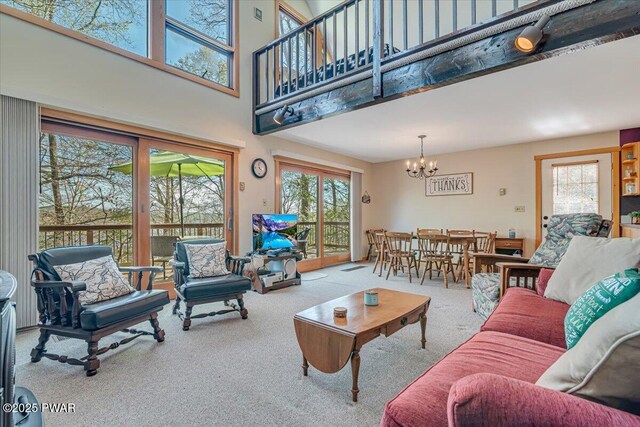 living room featuring a high ceiling, an inviting chandelier, a healthy amount of sunlight, and carpet