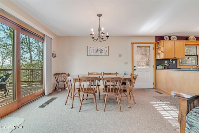 dining room with a chandelier, light colored carpet, visible vents, and plenty of natural light
