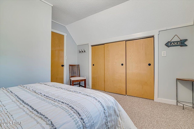 bedroom featuring a closet, carpet flooring, a textured ceiling, and vaulted ceiling