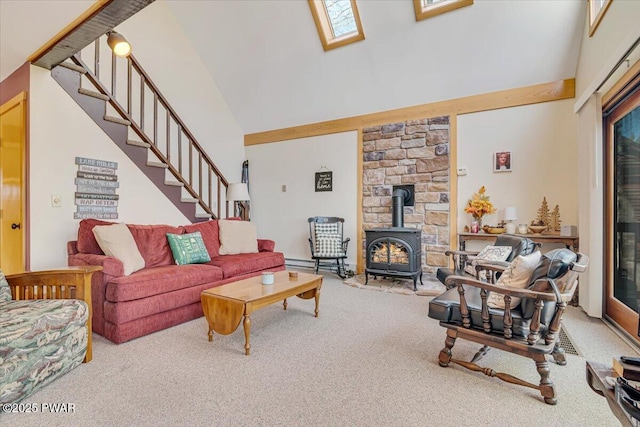 carpeted living area featuring a wood stove, high vaulted ceiling, a wealth of natural light, a skylight, and stairway