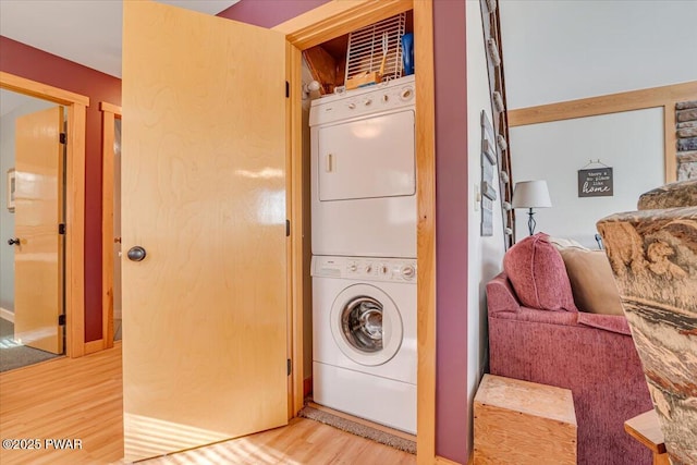laundry area featuring stacked washer / drying machine, laundry area, and light wood-type flooring