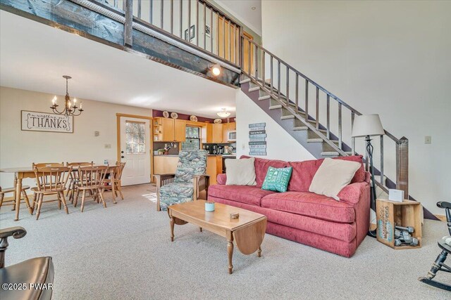 living area with stairway, a high ceiling, carpet flooring, and a notable chandelier