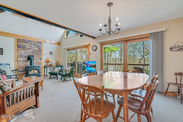 dining room featuring vaulted ceiling, a wood stove, a chandelier, and light colored carpet