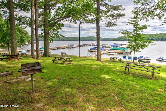 view of community featuring a boat dock, a water view, and a yard