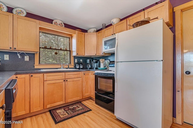 kitchen featuring light wood-style floors, dark countertops, white appliances, and a sink