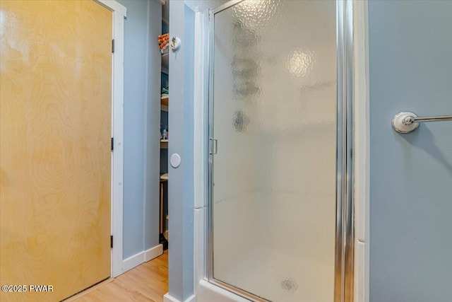 bathroom featuring baseboards, a stall shower, and wood finished floors