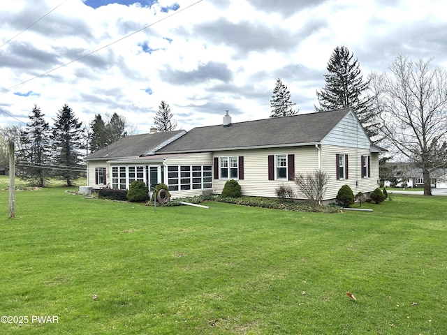 view of front of house featuring a chimney, a front lawn, and a sunroom
