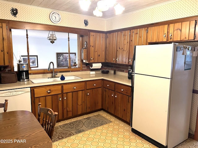 kitchen with a chandelier, white appliances, light countertops, and a sink