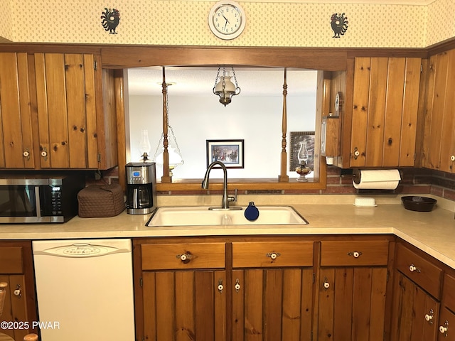 kitchen featuring stainless steel microwave, a sink, dishwasher, and light countertops