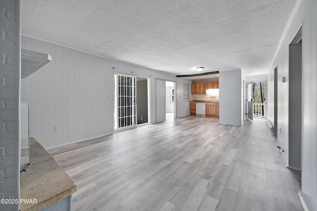 unfurnished living room with a textured ceiling, plenty of natural light, and light wood-type flooring