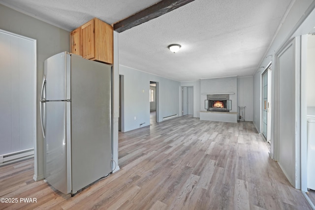 kitchen with baseboard heating, a textured ceiling, freestanding refrigerator, and light wood-style flooring