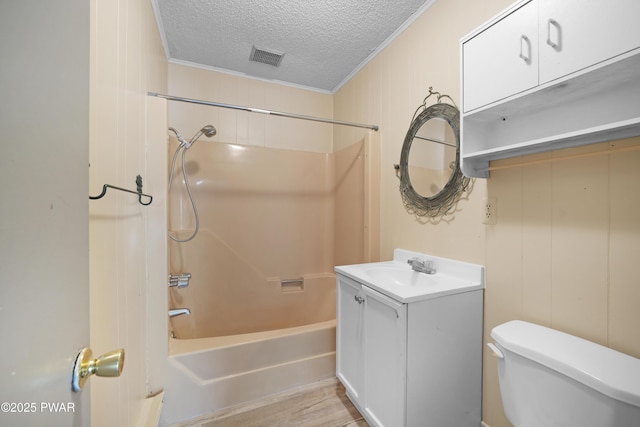 bathroom with a textured ceiling, shower / washtub combination, vanity, toilet, and ornamental molding