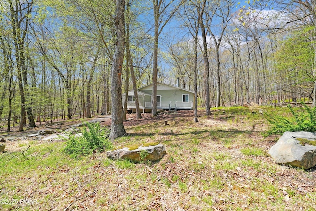 view of yard with a deck and a wooded view