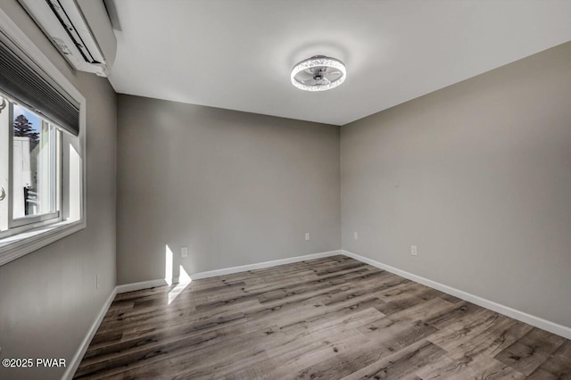 spare room with baseboards and wood finished floors