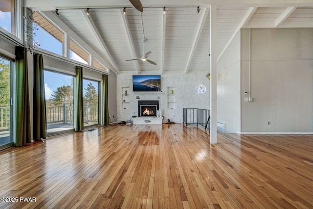 unfurnished living room featuring beamed ceiling, a fireplace, and wood-type flooring