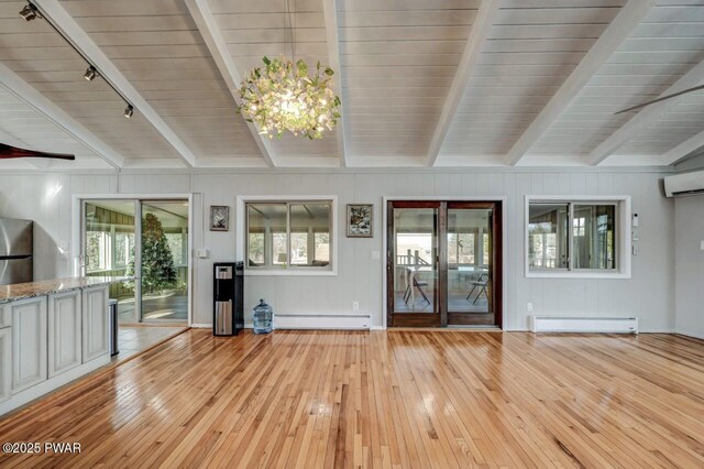 interior space featuring light wood finished floors, beamed ceiling, a wall mounted air conditioner, baseboard heating, and a baseboard radiator