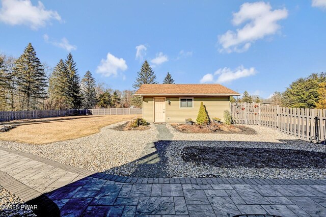 rear view of house featuring an outbuilding and a fenced backyard