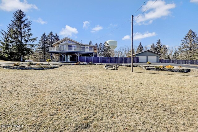 view of front facade featuring an outbuilding, a balcony, a front yard, fence, and a garage