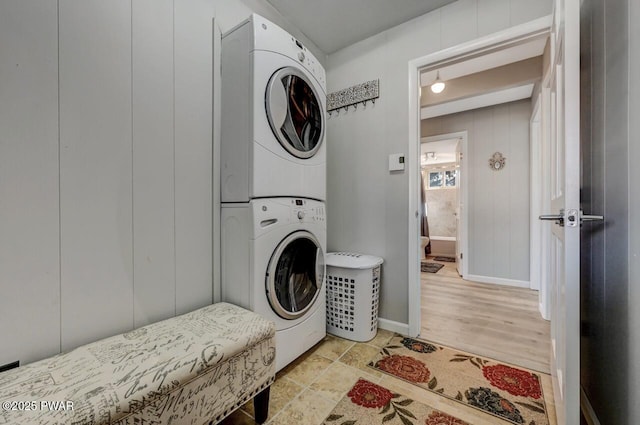 clothes washing area featuring laundry area, baseboards, and stacked washer / drying machine