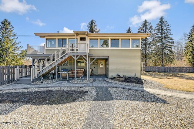 view of front of home featuring stairway, a deck, and fence