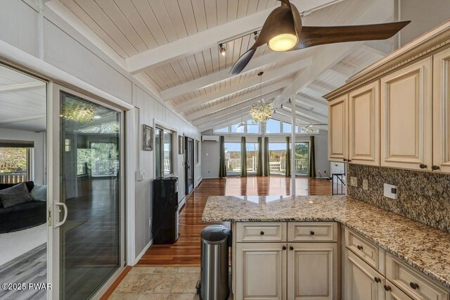 kitchen with lofted ceiling with beams, backsplash, cream cabinetry, and open floor plan